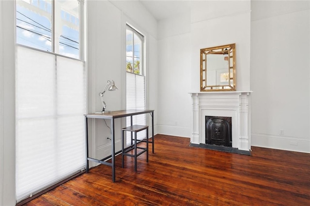 living area featuring a fireplace with flush hearth, wood finished floors, and baseboards