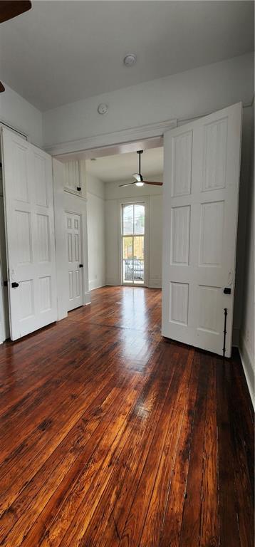 unfurnished room featuring ceiling fan and dark wood-type flooring