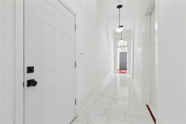 corridor with baseboards and marble finish floor