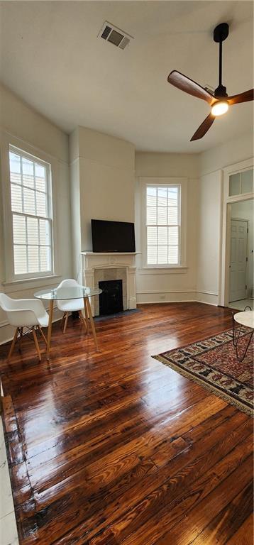 unfurnished living room with wood-type flooring, plenty of natural light, and ceiling fan