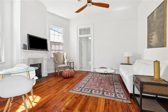 living room featuring a fireplace with flush hearth, wood-type flooring, and ceiling fan