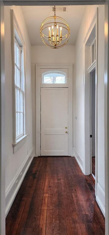 entryway with plenty of natural light, dark wood-type flooring, and a chandelier