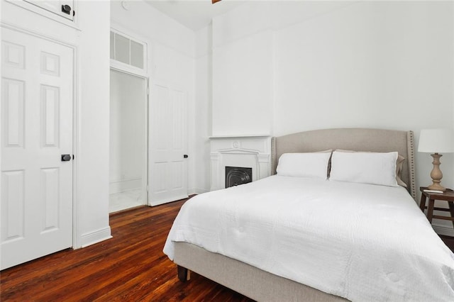 bedroom featuring baseboards, hardwood / wood-style floors, and a fireplace