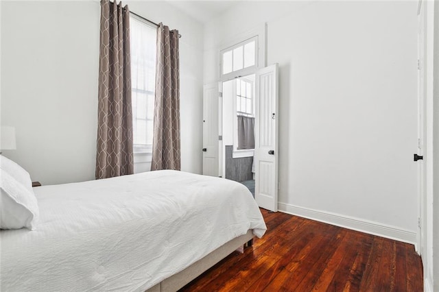 bedroom featuring baseboards, hardwood / wood-style flooring, and ensuite bathroom