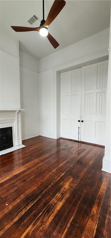 unfurnished living room with ceiling fan and dark wood-type flooring