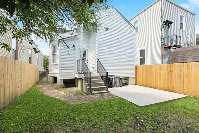 rear view of house featuring a fenced backyard, a yard, a patio area, and entry steps