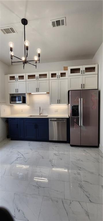 kitchen featuring sink, decorative backsplash, appliances with stainless steel finishes, decorative light fixtures, and white cabinetry