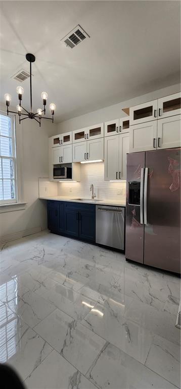 kitchen with white cabinets, sink, hanging light fixtures, and appliances with stainless steel finishes