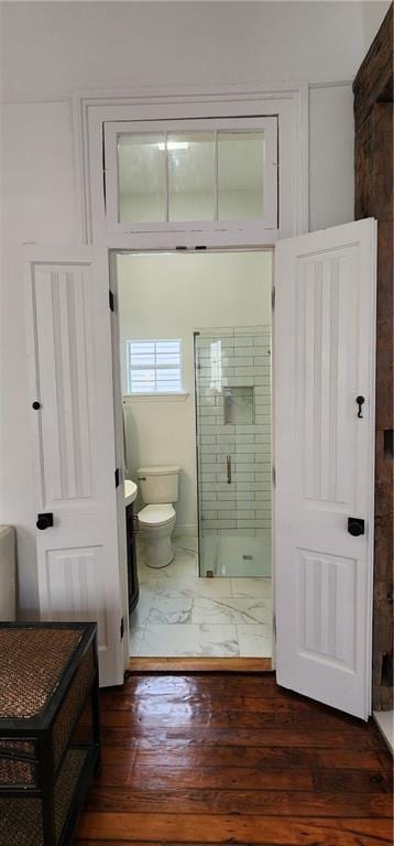 bathroom featuring hardwood / wood-style floors, a shower with shower door, and toilet