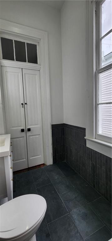 bathroom with tile patterned floors, tile walls, and a healthy amount of sunlight