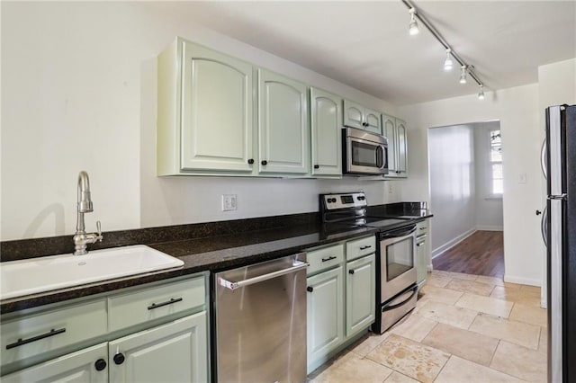 kitchen with appliances with stainless steel finishes, track lighting, green cabinetry, and sink