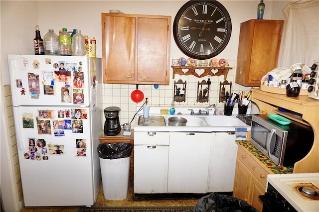 kitchen with backsplash, white appliances, and sink