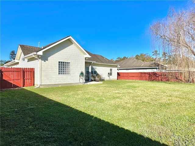 rear view of house featuring a fenced backyard, a yard, and roof with shingles