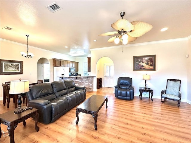 living area featuring arched walkways, visible vents, light wood-style floors, and ornamental molding