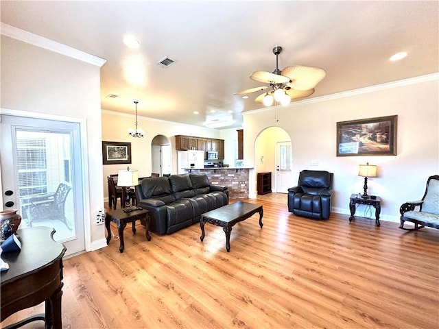 living area with visible vents, light wood-style flooring, arched walkways, ceiling fan, and crown molding