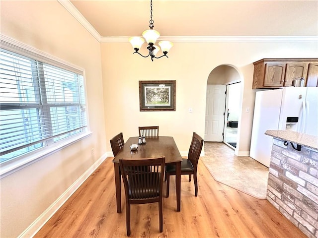 dining area featuring baseboards, light wood finished floors, an inviting chandelier, arched walkways, and ornamental molding