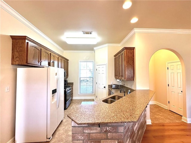 kitchen featuring visible vents, arched walkways, a sink, white refrigerator with ice dispenser, and gas range oven