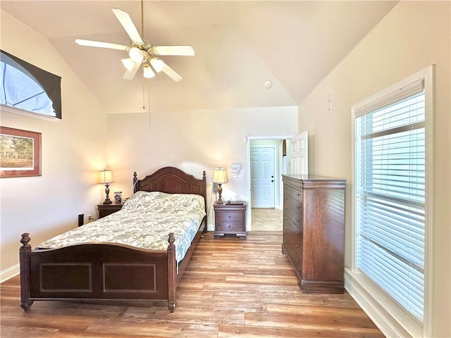 bedroom with ceiling fan, baseboards, lofted ceiling, and light wood-style flooring