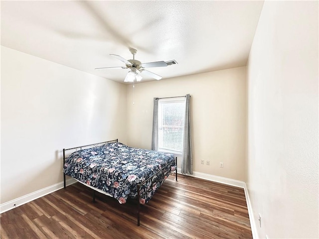 bedroom with visible vents, wood finished floors, baseboards, and ceiling fan