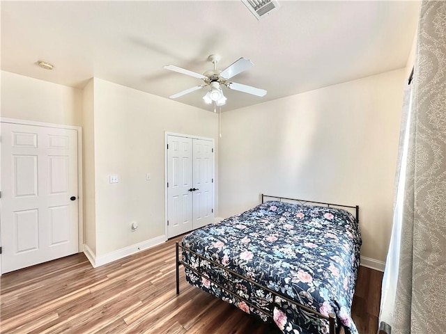 bedroom featuring a ceiling fan, wood finished floors, visible vents, and baseboards