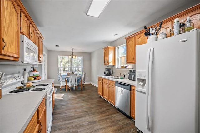 kitchen featuring sink, dark hardwood / wood-style flooring, a chandelier, pendant lighting, and white appliances