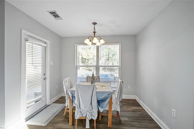 dining space with dark hardwood / wood-style floors and an inviting chandelier