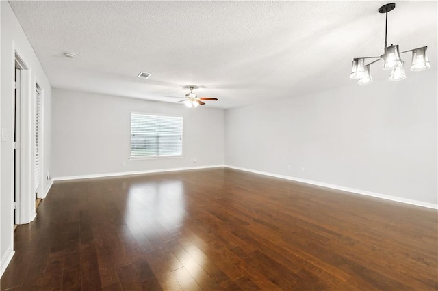 spare room with a textured ceiling, ceiling fan with notable chandelier, and dark hardwood / wood-style floors