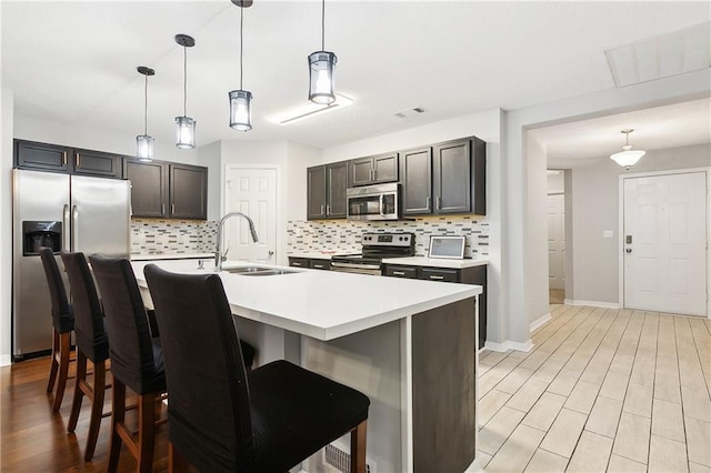 kitchen featuring a kitchen bar, pendant lighting, sink, and stainless steel appliances