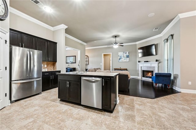 kitchen featuring sink, crown molding, tasteful backsplash, stainless steel appliances, and a kitchen island with sink