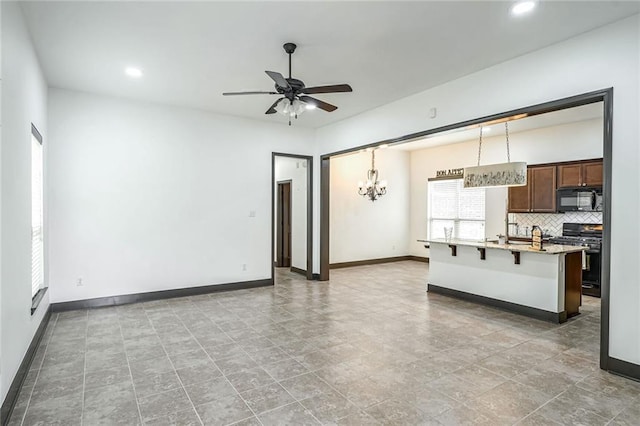 unfurnished living room with ceiling fan with notable chandelier