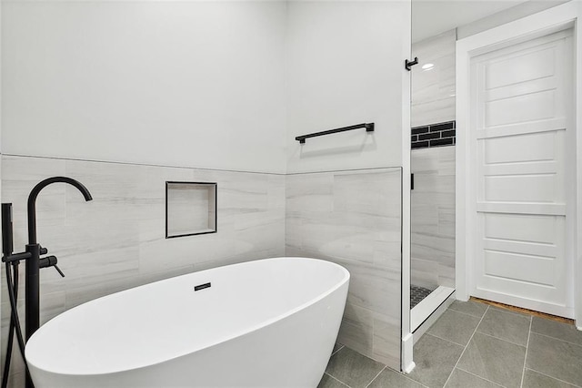 bathroom with tile patterned flooring, tile walls, and independent shower and bath