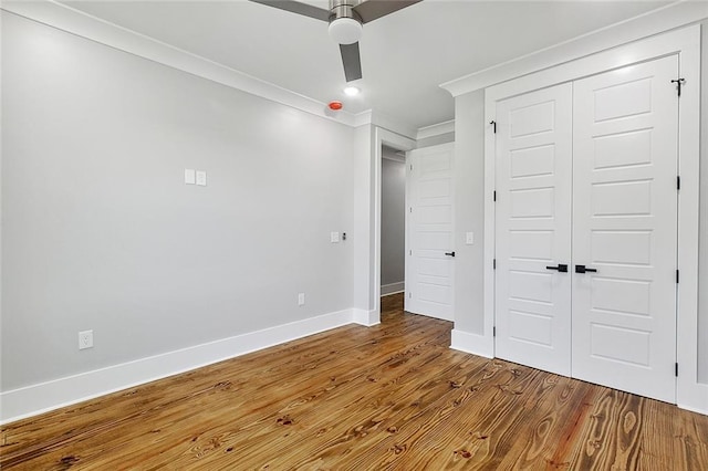 unfurnished bedroom featuring ceiling fan, a closet, crown molding, and hardwood / wood-style flooring