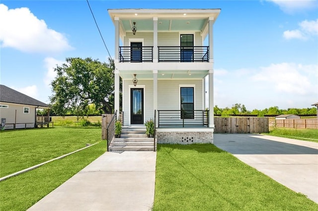 view of front of property featuring a front yard, a balcony, and covered porch