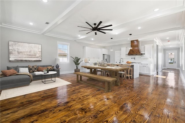 dining room featuring sink, dark hardwood / wood-style floors, ceiling fan, ornamental molding, and beamed ceiling