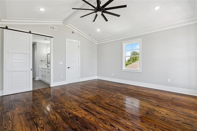 unfurnished bedroom featuring ensuite bath, ceiling fan, dark wood-type flooring, a barn door, and vaulted ceiling with beams