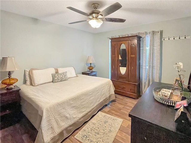 bedroom featuring ceiling fan, light hardwood / wood-style flooring, and a textured ceiling