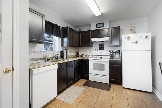 kitchen featuring white appliances, sink, light tile patterned floors, light stone counters, and dark brown cabinetry