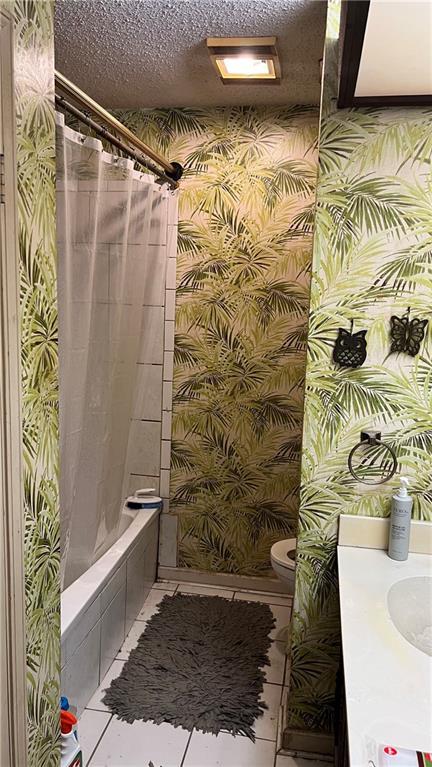 full bathroom featuring a textured ceiling, tile patterned flooring, shower / tub combo, and toilet