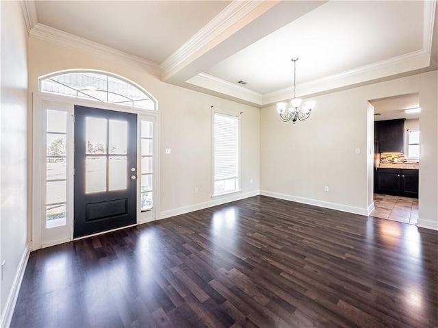 foyer with a notable chandelier, dark hardwood / wood-style floors, and crown molding