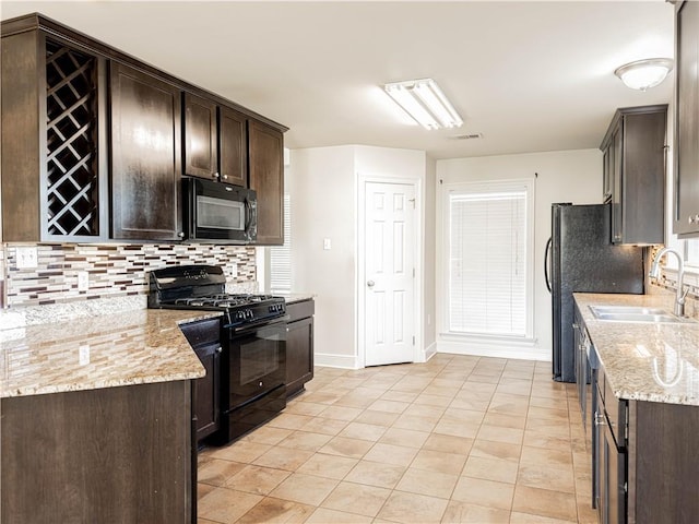 kitchen featuring light stone counters, sink, black appliances, and dark brown cabinets