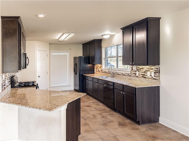 kitchen featuring black appliances, sink, light stone countertops, tasteful backsplash, and kitchen peninsula