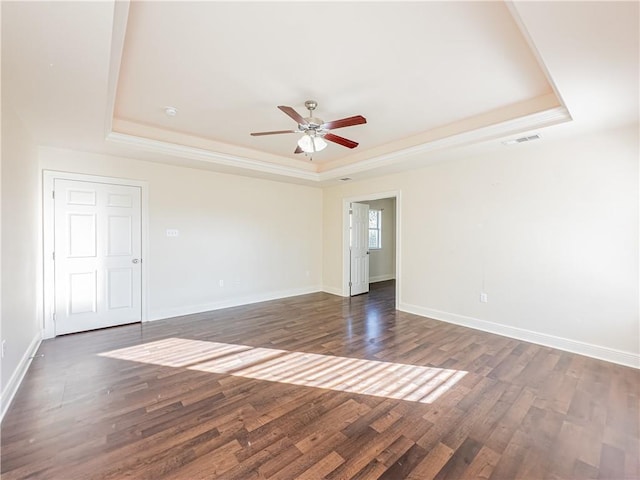 unfurnished room with a tray ceiling, dark hardwood / wood-style floors, and ceiling fan