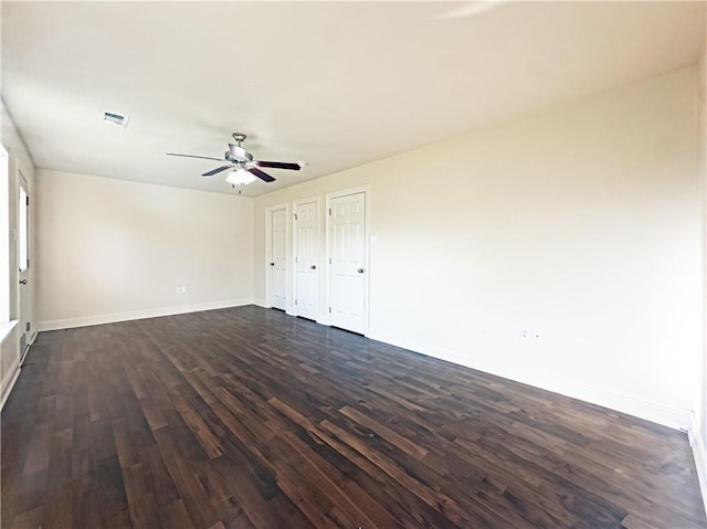 unfurnished bedroom featuring multiple closets, ceiling fan, and dark wood-type flooring