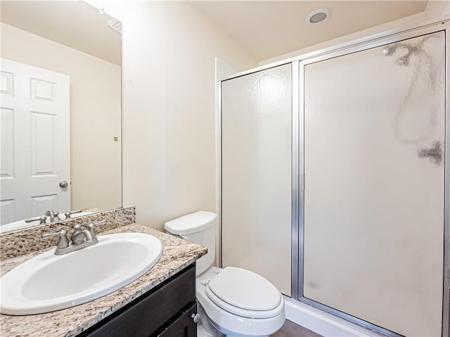 bathroom featuring vanity, a shower with shower door, and toilet