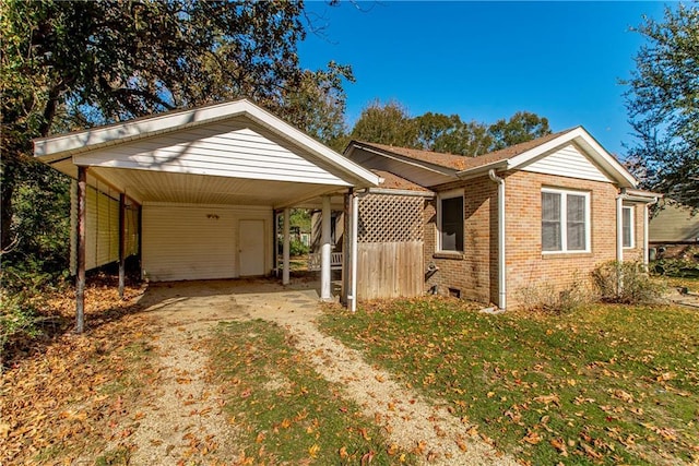 view of front of property with a front lawn, driveway, a detached carport, crawl space, and brick siding