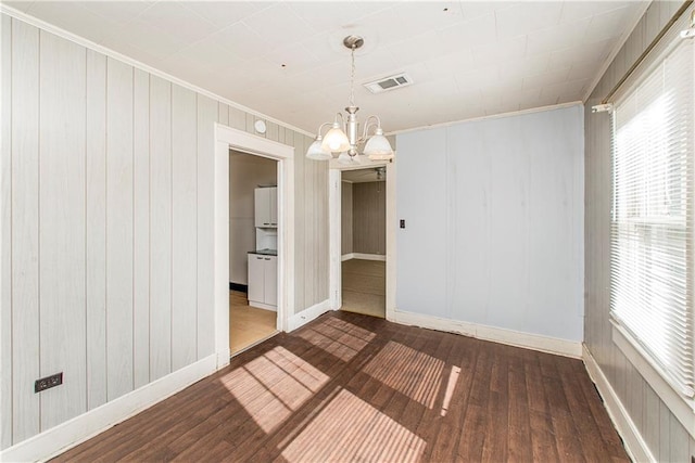 spare room featuring dark wood-style floors, visible vents, a wealth of natural light, and a notable chandelier