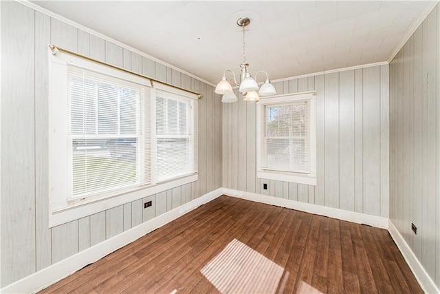 spare room with a notable chandelier, baseboards, and wood-type flooring