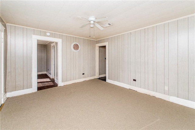 carpeted empty room featuring baseboards, a ceiling fan, and crown molding