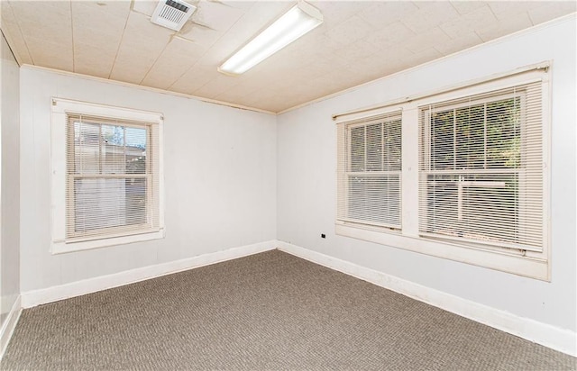 spare room featuring carpet flooring, baseboards, visible vents, and ornamental molding