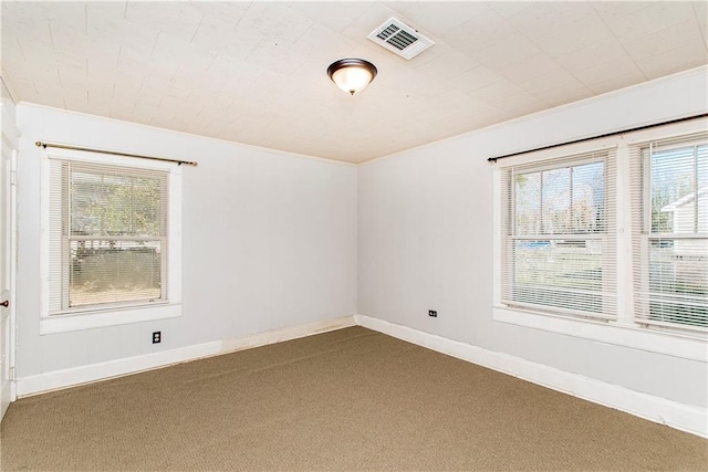 carpeted empty room featuring visible vents, crown molding, and baseboards